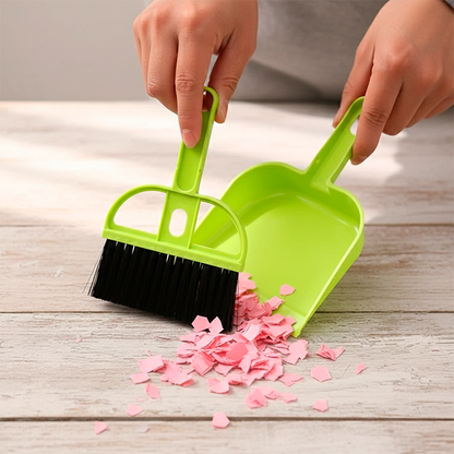 balayette pelle verte qui ramasse  des miettes du papier rose